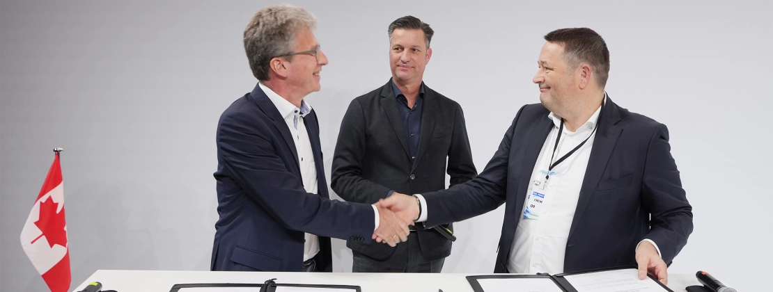 2 men shaking hands, 1 looking on