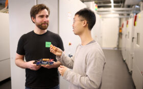 two men talking and holding batteries