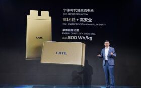 man in front of pic of batteries
