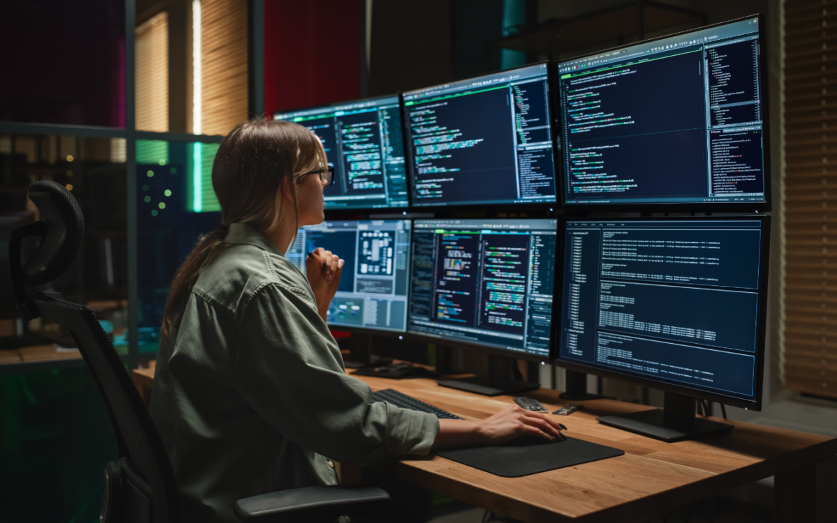 woman sitting and looking at bank of monitors