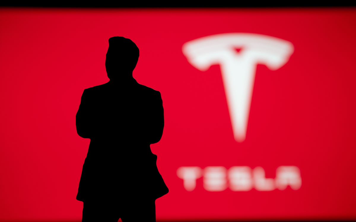 silhouette of man in front of tesla logo