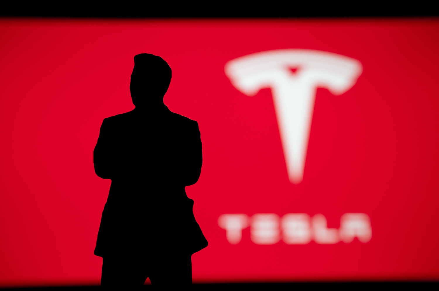 silhouette of man in front of tesla logo