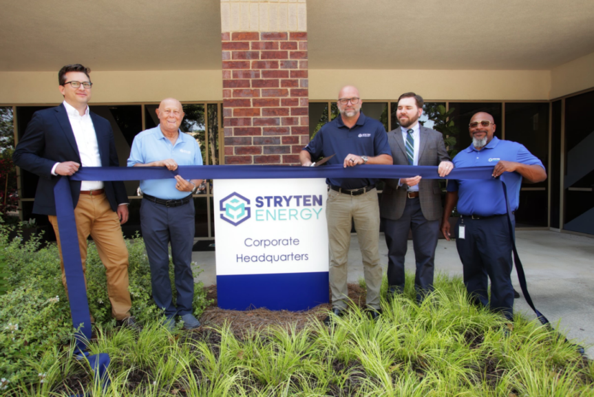 five men holding a blue ribbon, one about to cut it
