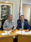 2 men at a desk signing a document