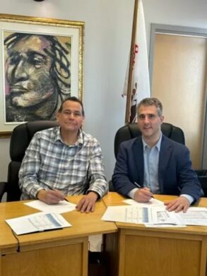 2 men at a desk signing a document